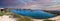 A breathtaking panoramic shot of the boats parked in the harbor near the jetty with gorgeous vast blue ocean water