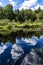 Breathtaking shot of a clear lake with the reflection of vibrant trees and the blue sky