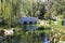 A breathtaking shot of a a stone bridge over a like with deep green lake water and lush green trees reflecting off the lake with b