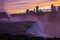 Breathtaking shot of a strong waterfall in the middle of a big city under the colorful sunset