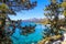 A breathtaking shot of vast blue lake water and lush green trees and snow capped mountain ranges