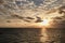 Breathtaking sunset in the middle of the ocean, with yellow orange blue sky and white clouds, View from the deck of cruise ship.