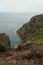 Breathtaking view of a person in red standing on rocks admiring the view of Normandy coastline.