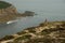 Breathtaking view of a person in red standing on rocks admiring the view of Normandy coastline.