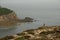 Breathtaking view of a person in red standing on rocks admiring the view of Normandy coastline.