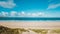 Breathtaking view of the sandy ocean by the calm ocean under the blue sky in Cornwall, England