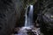 Breathtaking view of a waterfall between rocks in gorge with narrow staircase path