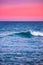 Breathtaking view of the waves of the ocean glimmering under the pink sky - great for wallpapers