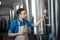 Brewery worker checking fermentation process in steel vat and look at notepad at plant