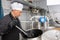 Brewery worker stirring raw materials in fermenter for beer production