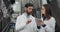 Brewery workers in white lab coats checking equipment. Man talking and giving instructions and woman using tablet while