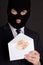 Bribery concept - masked man in suit holding envelope with euro