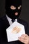 Bribery concept - masked man in suit holding envelope with money