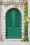 Brick archway with green wooden door, creeper at the right side, mediterranean architecture