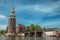 Brick bell tower and bridge at canal with moored boats and blue sky in Amsterdam.