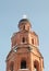 Brick bell tower with snow covered cross at snowfall