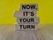 Brick blocks form the words \\\'now, it\\\'s your turn\\\' on a wooden table.