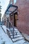 Brick building with stairs and glass entrance door viewed on a snowy winter day