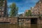 Brick buildings and bridge on canal with bicycles and sunny blue sky in Amsterdam.