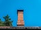 Brick chimney pipe against a blue sky