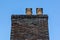 a brick chimney stack with clay chimney pots on top