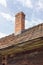 Brick chimney on tile roof of an old wooden house