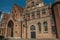 Brick facade of church, wooden door and blue sky in an alleyway of Bruges.