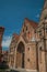 Brick facade of church, wooden door and blue sky in an alleyway of Bruges.