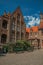 Brick facade of houses, bench and blue sky in a peaceful courtyard in Bruges.