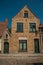 Brick facade of old houses and doors with blue sky, in an empty street of Bruges.