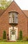 Brick house with bay window centered above the arched marble tiled door with statues of greyhoud dogs flanking the prorch -