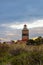 A brick lighthouse with a bright blue sky in the background. Picture of Falsterbo Lighthouse from 1796 in Scania