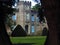 Brick manor house with topiary front yard enclosed by tree trunks.