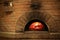 Brick oven with burning firewood and pizzas