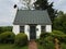 Brick path or trail with green bushes and house or shed with bell and trees