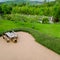 Brick paved patio with comfortable patio furniture with rustic armchairs and a stool surrounded by garden, high angle view