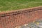 Brick retaining wall with dirt stained mortar, green grass and concrete