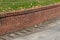 Brick retaining wall with green grass and concrete driveway, residential