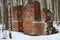 Brick ruins, remains of abandoned building, crumbling red brick walls in depths of the winter forest