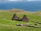 Brick stone structures in the Riasg Buidhe village, the Shetland with fresh grass and a sea above