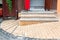 Brick threshold on the slope with granite steps to the open wooden entrance door.