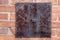 Brick wall of home exterior with large metal plate attached rusted with age
