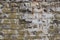 Brick wall with layers of grey, white, and green peeling paint