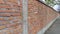 Brick wall made of bright red bricks around a catholic cemetery. The fence is 2 meters high. Cement between the rows. Grunge