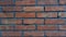 Brick wall made of dark red bricks. Lightly worn surface. Neat masonry, cement between the rows. Grunge background. The exterior