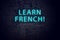 Brick wall and neon sign with inscription. Concept of learning french