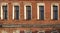 Brick wall of an old 19th century building with large windows. Wall of an old red brick building with five windows