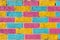Brick wall painted in bright yellow, blue and pink colors