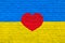 Brick wall is painted in the colors of the Ukrainian national flag - yellow and blue and red heart in the middle