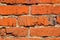 Brick wall of red uneven bricks. Close-up